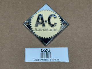 Allis Chalmers Cream Emblem Steering Wheel, display of a vintage metal automobile emblem with cream and black coloring, featuring the Allis Chalmers logo.