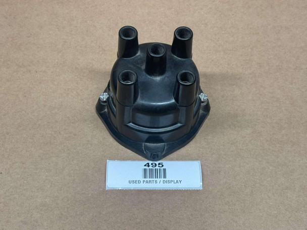 Distributor Cap ACR1954, black plastic engine distributor cap with multiple ignition wire connectors, used automotive part displayed on a plain surface.