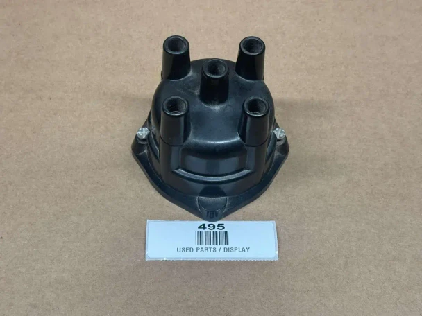 Distributor Cap ACR1954, a black automotive distributor cap with six ports for spark plug wires, displayed on a brown background with a label indicating it's a used part.