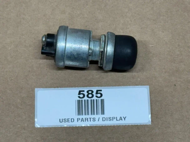 Universal 2 Terminal Push Button Starter Switch and Ether Switch (Display), close-up of a metallic switch with black rubber end on a brown surface with a label marked '585' and 'USED PARTS / DISPLAY'.