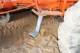 Metal step mounted beneath an orange Allis-Chalmers farm tractor, with a blue-gray vertical support and treaded footplate beside the large rear tire.