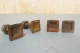 A row of rusty square head bolts, with some bolts lying on their sides and others standing upright. The background is a plain light-colored surface.