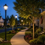 LED decorative post top lights illuminating a residential community sidewalk with landscaped pathway at dusk