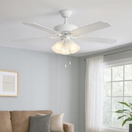52 inch white ceiling fan with light, 5-blade MDF design, 3-bulb fixture, warm white 3000K output, shown installed in a bright living room with white curtains and soft gray walls.