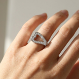 White gold heart ring worn on model's hand, front view of open heart statement ring with pavé finish