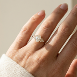 Dainty oval diamond ring with side stones yellow gold worn on hand natural diamond