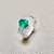 Top-down view of oval emerald ring with diamond halo 18kt white gold
