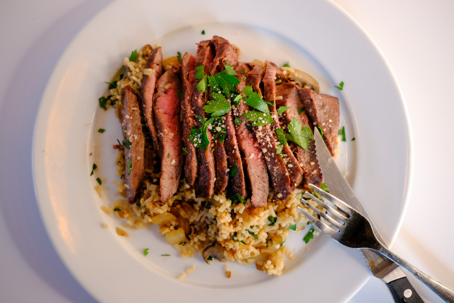 Slices of medium-rare steak served over a bed of low-carb rice with mushrooms.