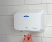 A woman using the Frost 1195 Eco-Friendly Automatic Hand Dryer in white, mounted on a tiled wall, showcasing the product's sleek design and touchless, energy-efficient technology in action.