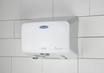 A woman using the Frost 1195 Eco-Friendly Automatic Hand Dryer in white, mounted on a tiled wall, showcasing the product's sleek design and touchless, energy-efficient technology in action.