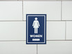 Frost 961 female washroom signage in a bold blue with white pictogram and Braille, ensuring clear and accessible directions for women's restrooms.