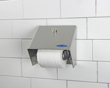 Frost 156-S stainless steel single roll toilet tissue dispenser mounted on a white tiled bathroom wall, featuring a clean design with a protective hood. Mounted on wall