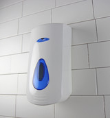 The Frost 707-2L white manual liquid soap/sanitizer dispenser mounted on a tiled wall, prominently featuring a large blue window for soap level visibility and a spacious push button for dispensing.