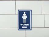 Frost 961 female washroom signage in a bold blue with white pictogram and Braille, ensuring clear and accessible directions for women's restrooms.