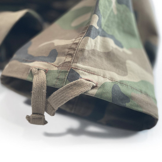 A close-up of the hem of camouflage drawstring pants with buttonholes after hemming alterations to shorten the inseam.
