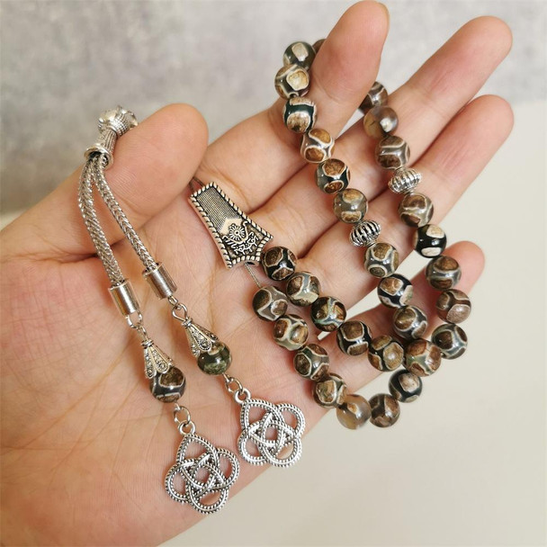 Round agate tasbih beads and engraved silver connector held in hand