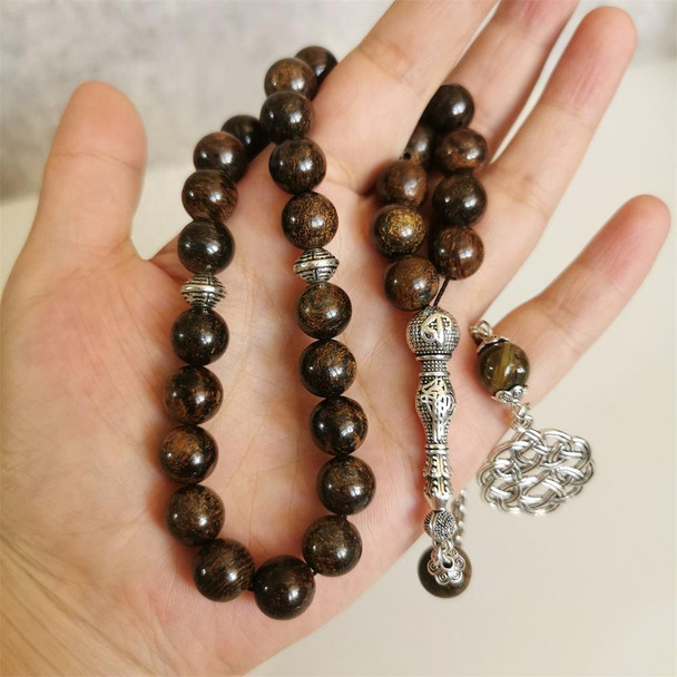 Brown Muslim Prayer Beads with Silver Pendant Held in Hand