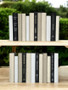 Natural, white, and taupe parchment bound spines with a touch of modern hardbound books in black for a very clean look. Book covers vary.- 24 books / 8.5-9.5"