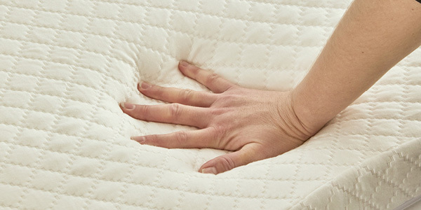 Hand pushing down mattress to see if it's worth getting a mattress topper