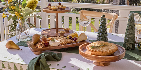 Food sits on top of acacia serveware on a table decorated for Christmas