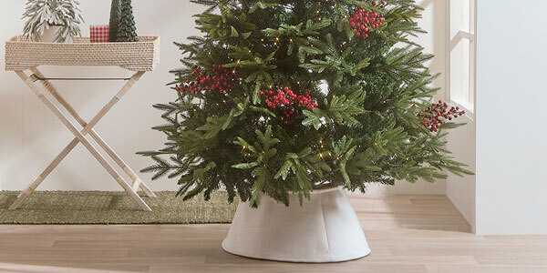 A Christmas tree with lights, holly berry stems and a white Christmas tree skit. 