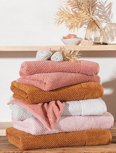 Pillow Talk Bath Towel buying guide Colourful stack of bath towels on a bench