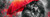Elly AI romantic couple embracing beneath a bright red umbrella in the rain with dramatic black white and crimson painted textures