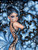 Elegant woman in a shimmering ice blue gown surrounded by enormous blue and black flowers beneath a sparkling starry sky.