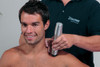enPuls 2.0 radial pulse shockwave handpiece positioned at the shoulder region in a professional clinical setting.