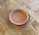 Deroma Terra Cotta - Saucer 4.3 inch, round terracotta plant saucer on wooden surface. Deroma Terra Cotta - Saucer 4.3 inch, round terracotta plant saucer on wooden surface.
