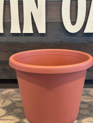HC Companies, Inc. Classic Prima Planter 16in, large coral-colored plastic plant pot with smooth surface and rounded rim, placed on a patterned floor with wooden wall background.