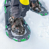 Close-up of adult snowshoe binding on patterned green snowshoes, strapped over hiking boots in snow Close-up of adult snowshoe binding on patterned green snowshoes, strapped over hiking boots in snow