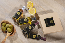 White paper gift box containing four bottles of assorted flavors of olive oil and balsamic