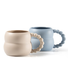 a Blue and an off-white mug with whimsical beadlike handles