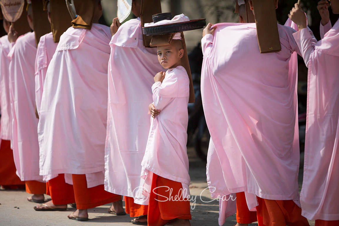 A photograph of a curious young Buddhist nun looking back in Mandalay, Myanmar by Shelley Coar.