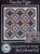 Colorful quilt pattern featuring circles, stars, and rainbow triangles on white and black background, suitable for intermediate quilters.