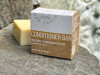 One Earth Body Care Conditioner Bar for Medium / Combination Hair, Patchouli-Fir aroma. Naked square conditioner bar next to compostable box package. One Earth Body Care Conditioner Bar for Medium / Combination Hair, Patchouli-Fir aroma. Naked square conditioner bar next to compostable box package.
