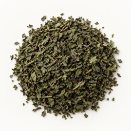 Image - Loose dried peppermint leaf on a warm-white background.
