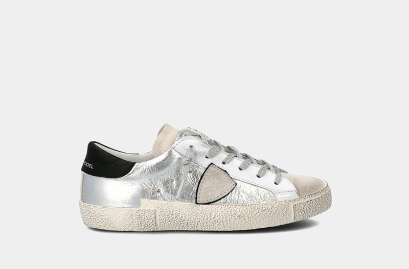 Side view of Philippe Model sneaker. This sneaker has the company logo with white leather and sparkly silver shoelaces. 