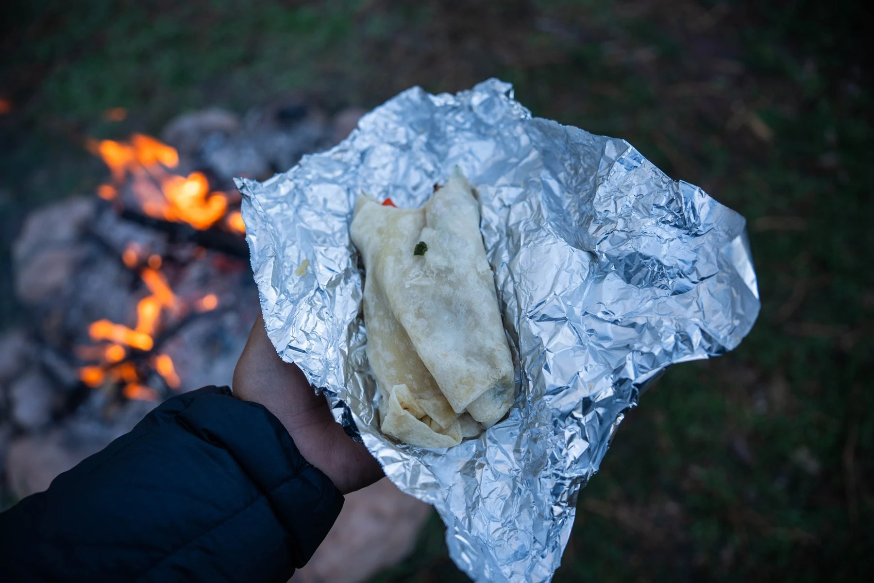 A breakfast burrito beside the morning campfire.