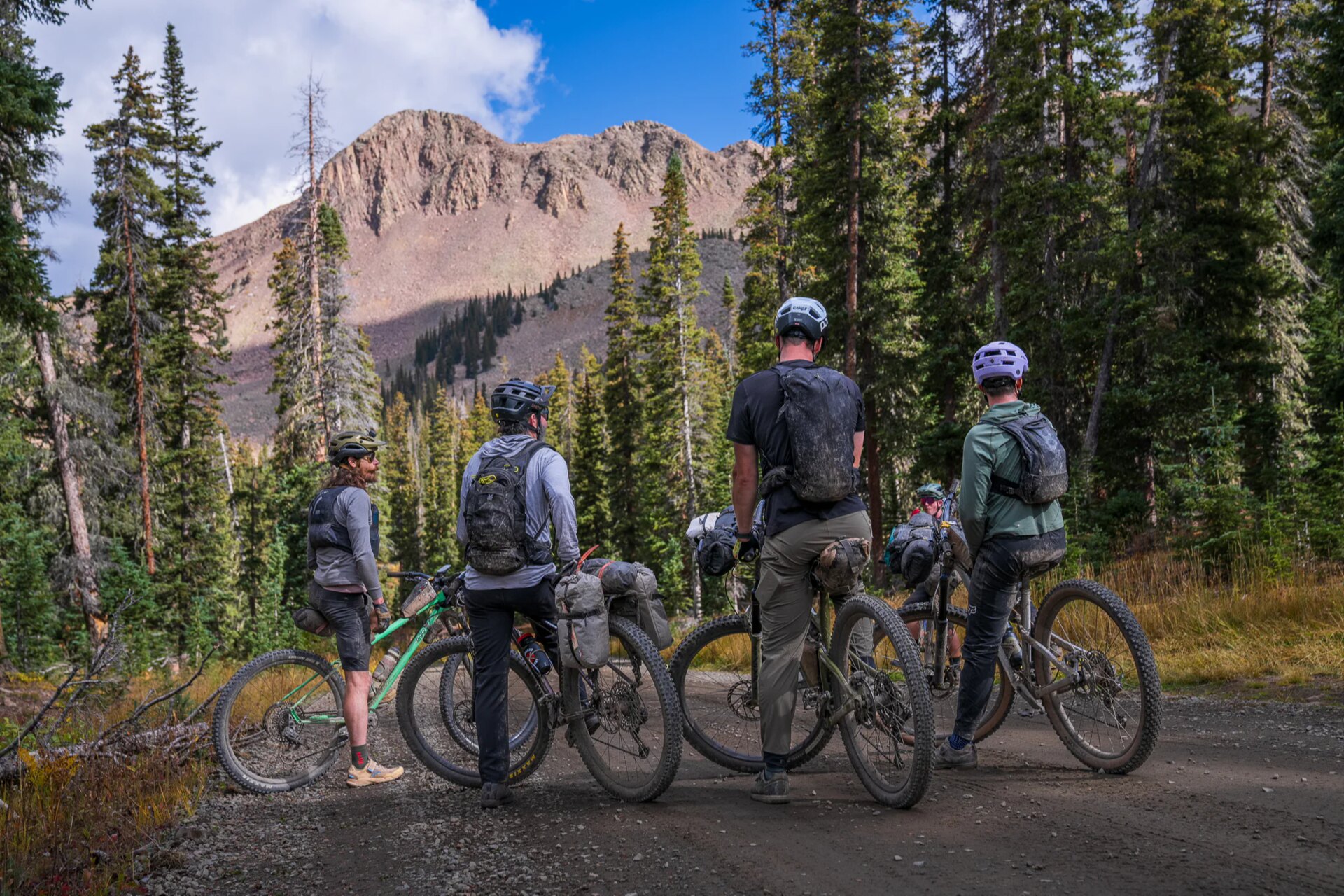 Esker riders pause beneath a mountain ridge