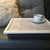 smoke grey lap tray with cream frame, grey cushion and a coffee cup on top of it