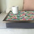 Botanicals turquoise lap tray with silver frame and grey cushion with coffee cup on top of it