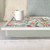 green floral lap tray with cream frame and green cushion on a sofa