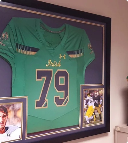 A framed green Notre Dame football jersey on a wall