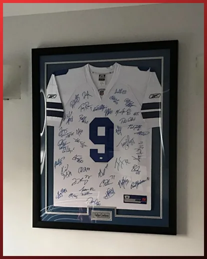 A signed white football jersey in a black frame