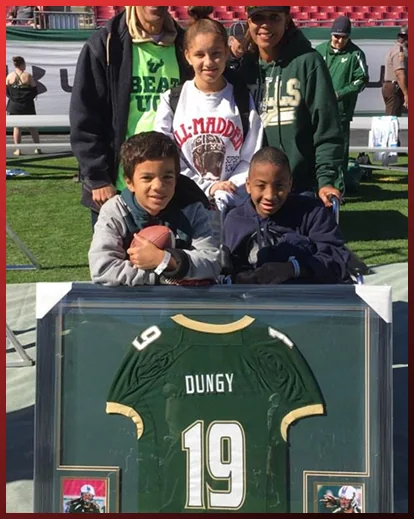 A family beside a framed Tony Dungy jersey