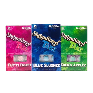 A side-by-side comparison showcase of Shrumfuzed Tabz 12,000mg mushroom tablet boxes in Tutti Frutti, Blue Slushee, and Eden's Applez flavors highlighting the 15-count blister packs.