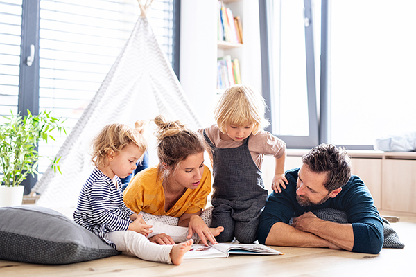 Family sitting comfortably on the floor while reading a book