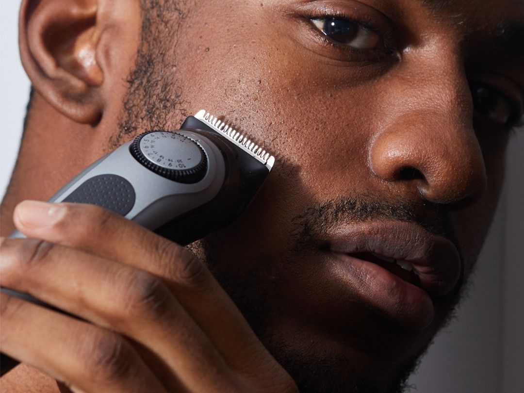 Man holding the series 7 all in one trimmer and trying to trip his beard